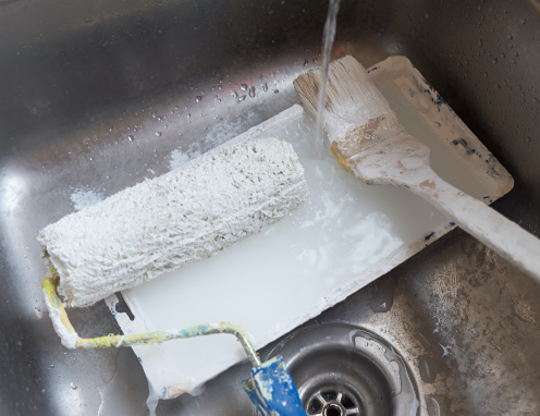 Ein Farbroller mit Lösungsmittel wird in einem Waschbecken gewaschen.