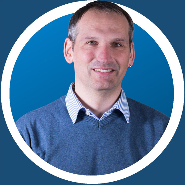 Ein Mann in einem blauen Pullover mit blauem Hintergrund.