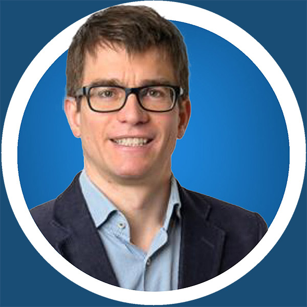 Ein Mann mit Brille lächelt vor einem blauen Kreis.