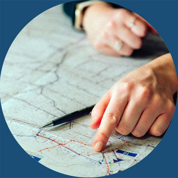 Eine Person zeigt mit einem Stift auf eine Karte.